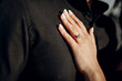 Engagement ring with a precious stone on a woman's finger close-up. A woman's hand with a wedding ring on the chest of a beloved man. An offer of marriage. Man wearing a black shirt