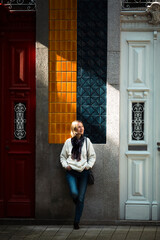 Wall Mural - A woman enjoys the sunlight while standing outside a traditional Portuguese town house.