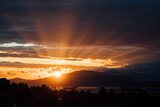Fototapeta Mapy - The evening sun drops behind the mountains behind English Bay, Vancouver, BC