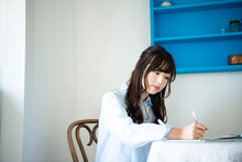 机に座ってノートに何かを書いている女性