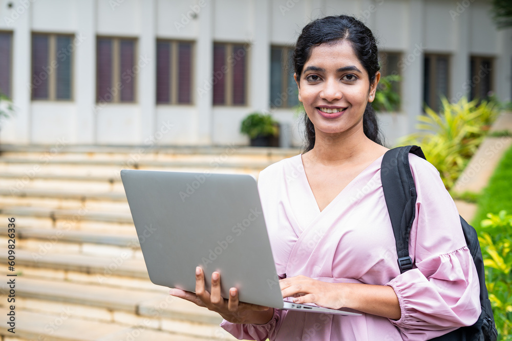 Confident girl student with backpack holding laptop by looking at ...