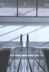 Wall Mural - Light and shadow on white tiles floor surface in building entrance area of shopping mall in monochrome style, view through the escalator railing and vertical frame