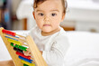 © Anela Ramba/peopleimages.com - Abacus, bedroom and baby play with toy for learning, child development and motor skills. Family home, newborn and face of adorable child with educational toys, counting beads and playing in bed