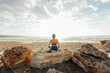 © Westend61 - Woman meditating sitting on rock at beach