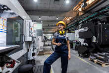 Smiling maintenance engineer standing by CNC machine in modern factory