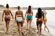 © Westend61 - Friends in swimwear walking on sand at beach