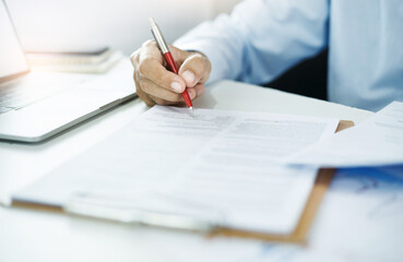 Asian businessman reviewing document reports at office with computer laptop, legal expert, professional lawyer reading financial documents or insurance contract before signing the contract