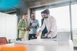 © Westend61 - Businessman explaining blueprint to coworkers at table in office