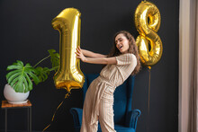 Playful Young Woman Holding Number 1 Helium Balloon At Home