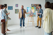 © pressmaster - Gallery owner presenting modern art of artist to group of people during exhibition in art gallery