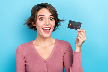 Poster - Photo of astonished pretty girl hand hold plastic debit card isolated on blue color background