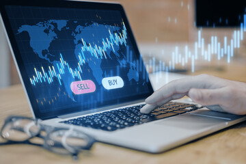 Poster - Close up of male hand using laptop computer with glowing blue sell and buy buttons, map and candlestick forex chart on blurry background. Trading and exchange concept.