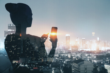 Poster - Back view of thoughtful businesswoman silhouette using cellphone while standing on dark night city background. Success, work, communication and lifestyle concept. Double exposure.