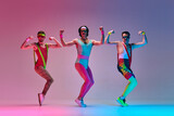 Sport show. Three funny men in colorful sportswear doing aerobics exercises against gradient blue pink studio background in neon light. Concept of sportive and active lifestyle, humor, retro style. Ad