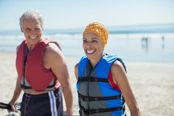 Wall Mural - Enthusiastic couple in life jackets on beach