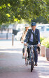 Businessman in suit and helmet riding bicycle on path