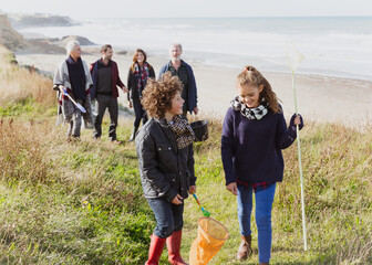 Wall Mural - Multi-generation family with nets walking on sunny grass beach path