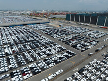 Aerial View Of New Cars Stock At Factory Parking Lot. Above View Cars Parked In A Row. Automotive Industry. Logistics Business. Import Or Export New Cars At Warehouse. Big Parking Lot At Port Terminal