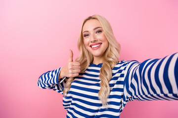 Poster - Photo of cute friendly woman wavy hairdo dressed striped shirt showing thumb up nice job doing selfie isolated on pink color background