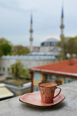 Wall Mural - Cup of fresh black Turkish coffee with view to Yeni Valide Mosque in Uskudar district in Istanbul, Turkey