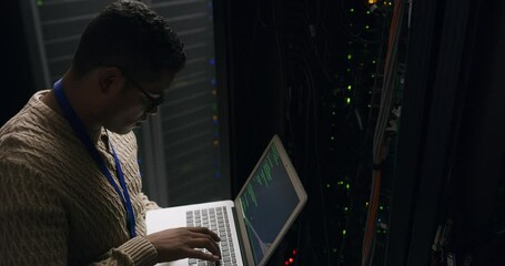 Wall Mural - Man in data center with laptop, coding and cybersecurity, network administration and engineer in digital storage. Tech employee, system maintenance and technician online in dark server room to code.