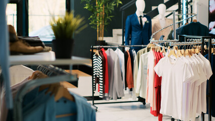 Interior of clothing store with stylish merchandise on racks, fashionable brand design and casual wear in modern boutique. Empty fashion showroom in shopping centre with elegant merchandise.