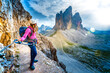 © Michael - Young athletic woman enjoys scenic view on Tre Cime from via ferrata in the evening. Tre Cime, Dolomites, South Tirol, Italy, Europe.