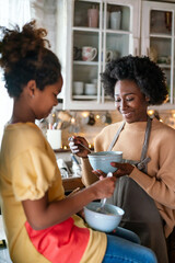 Wall Mural - Happy black mother and daughter having breakfast and spending quality time together in kitchen
