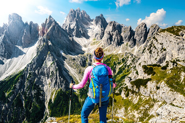 Wall Mural - Athletic woman enjoys epic view on Cadini group in the morning. Tre Cime, Dolomites, South Tirol, Italy, Europe.