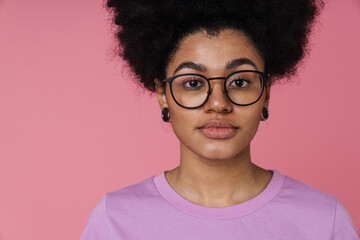 Wall Mural - African woman looking at camera while standing isolated over pink wall