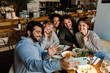 © Drobot Dean - Group of joyful friends taking selfie while dining in restaurant