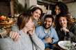 © Drobot Dean - Group of cheerful friends taking selfie while dining in restaurant
