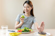 © Pormezz - Woman on dieting for good health concept. Close up female using hand push out her favourite donut and choose salad vegetables for good health.