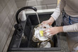 female hands washing dirty dish holding soap foam sponge in the kitchen