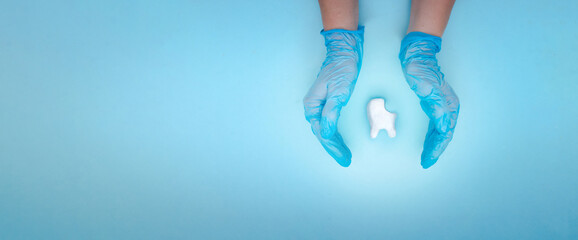 Woman hand holding unhealthy tooth white molar model on pastel blue background. Tooth symbol sign. Caries. Caries and disease of tooth. Unhealthy teeth. Creative medical dentistry. Tooth model.