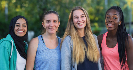 Wall Mural - Group of Young Multiethnic Female Teenagers in Sports Clothes Hugging and Posing for Camera in an Outdoors Working out Area. Girls Celebrating their Friendship by Taking a Group Photo