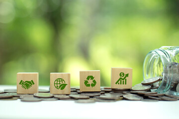 Green icons on wooden cubes on money coin stack. Green business