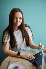 Aufkleber - Beautiful young woman drawing a sketch with a stylus pen on a tablet computer in a cafe. Freelance graphic designer female working in a restaurant