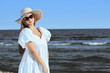 © rogerphoto - Happy blonde woman is posing on the ocean beach with sunglasses and a hat. Evening sun.