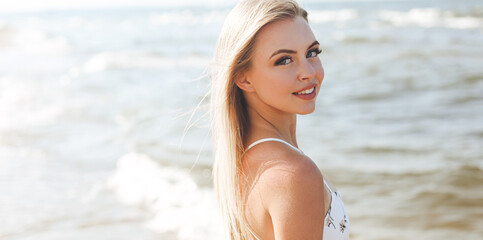 Happy blonde woman in free happiness bliss on ocean beach standing straight and posing.