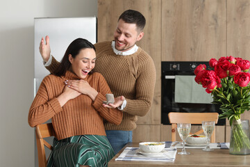 Sticker - Young man proposing to his happy girlfriend in kitchen