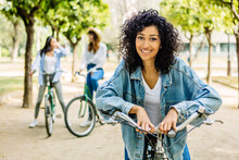 Portrait Of Young Beautiful Girl With Rental Bicycle Smile At Camera Outdoors. Female Friends Hanging Out Enjoying Summer Vacation Together Outdoors. Travel And People Concept.