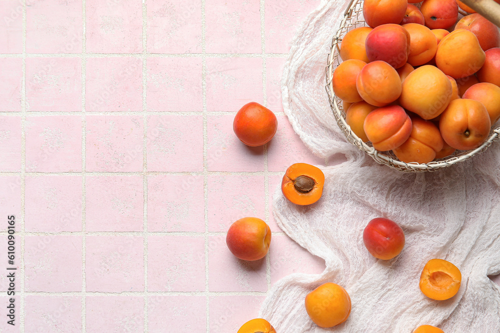 Basket with fresh apricots on pink tile background