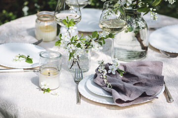 Rustic zero waste wedding decor with natural elements. Fresh spring blooming flowers, candles, linen napkins, wine glasses. Eco friendly decoration for the special holiday dinner. Romantic cozy place