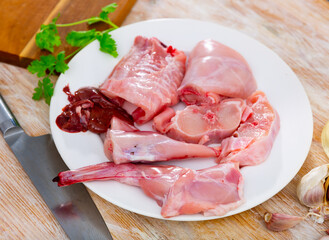 Canvas Print - Chopped rabbit with garlic and spices on white plate with knife in restaurant