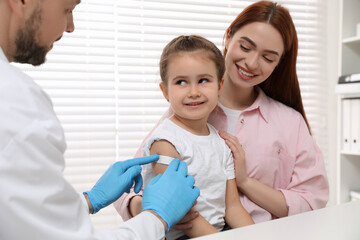 Poster - Children's hepatitis vaccination. Mother with her daughter in clinic. Doctor sticking medical plaster on little girl's arm