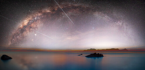 Wall Mural - the milky way galaxy over the sea and silhouette of rock in the night sky