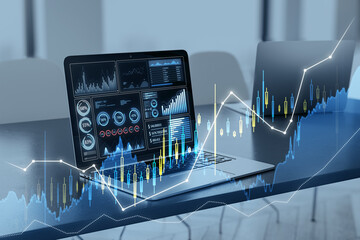 Poster - Close up of laptop at desk with glowing candlestick forex chart on blurry background. Trade, finance and technology concept. Double exposure.