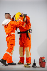 Wall Mural - Professional firefighter is helping his partner wearing a yellow hard hat on a white background.