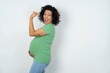 © Jihan - Profile side view portrait young pregnant woman wearing green t-shirt over white background celebrates victory